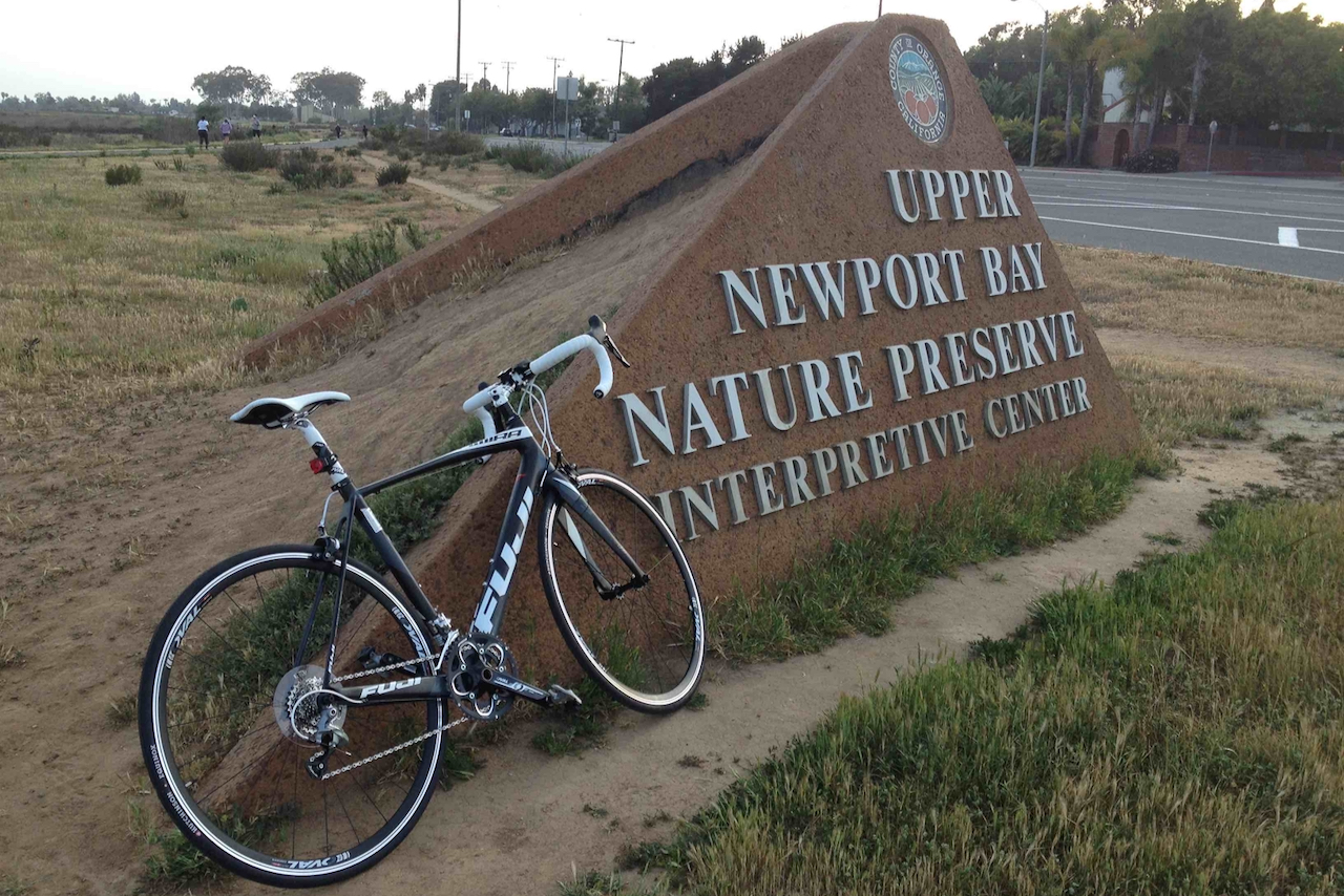 Every cyclist has their origin story and this one is mine. Image contains: Fuji Altamira bicycle, Newport Bay Nature Preserve, Newport Back Bay, sign, path, road.