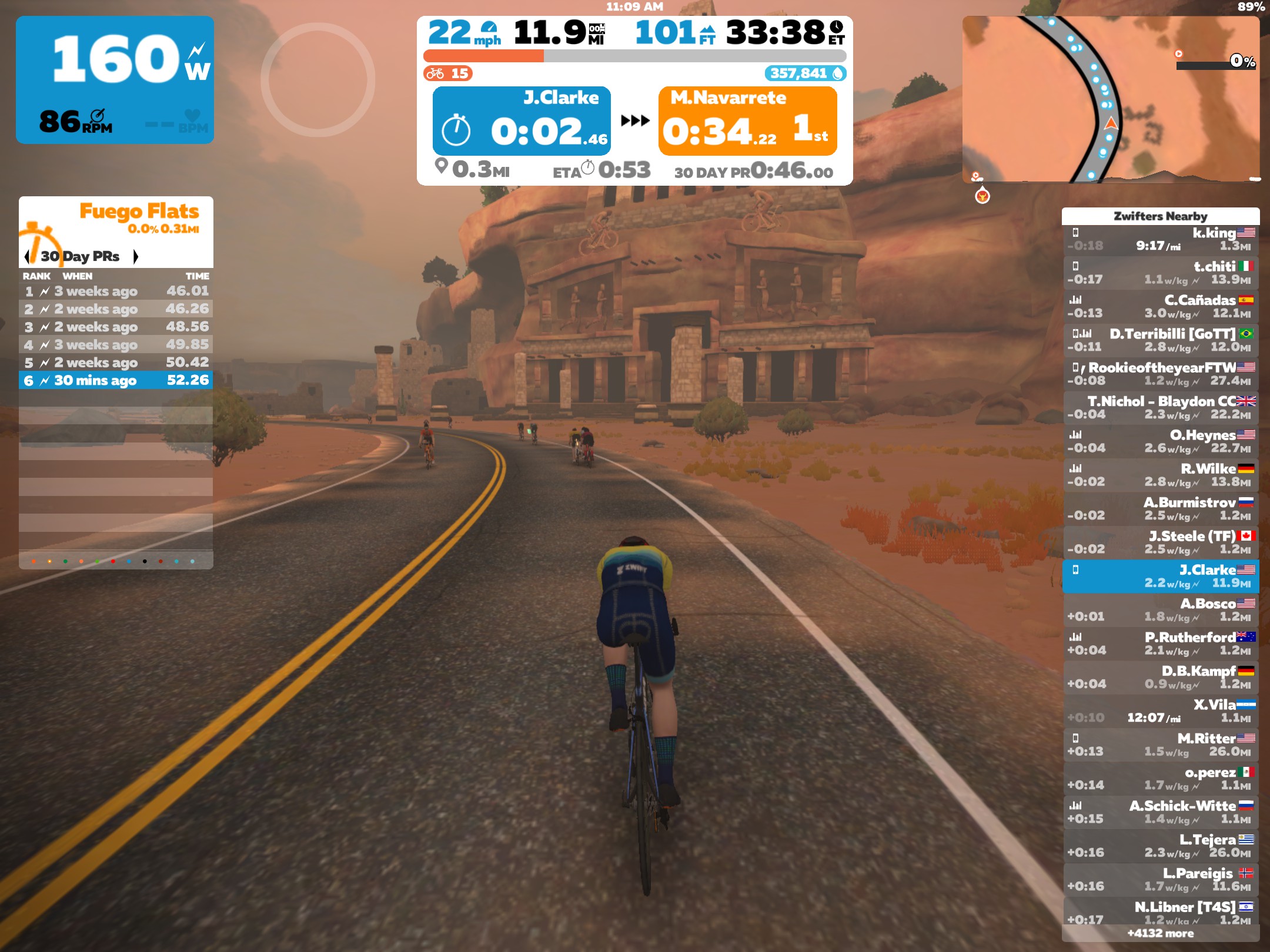 A virtual world within Zwift with a cyclist avatar riding a bike through the desert