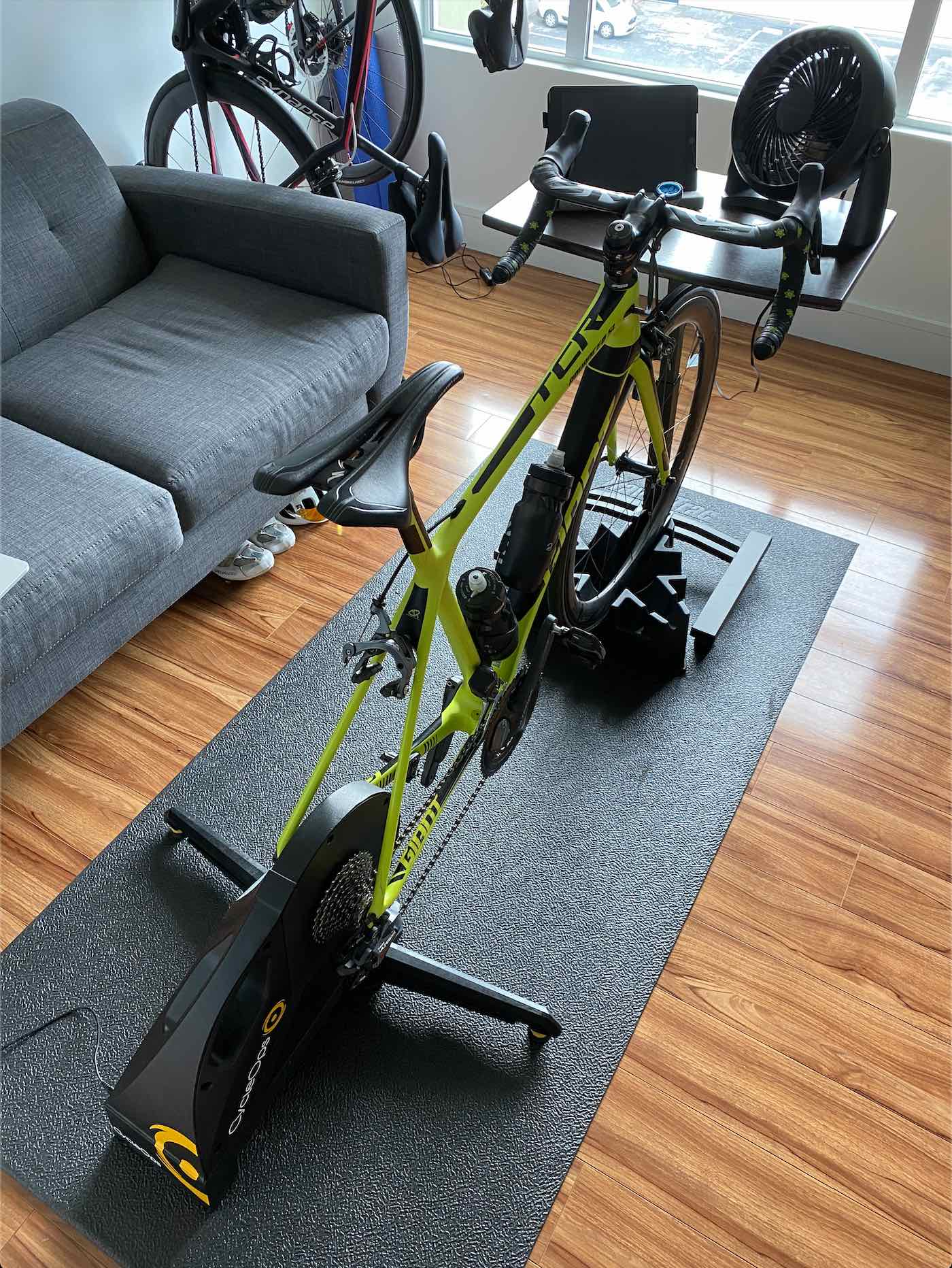 A Giant TCR bicycle mounted into a direct drive smart trainer indoors overlooking a window with a small desk in front