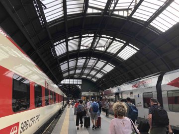 Train platform with train cars and people walking at the Milano Centrale train station in Milan, Italy