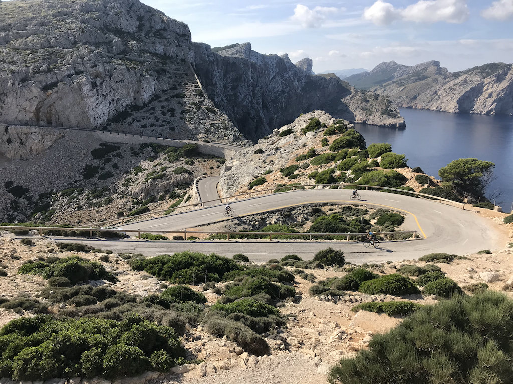 Cyclist climbing to the light at the top of Cap de Formentor in Mallorca, Spain