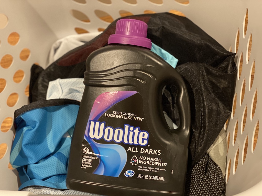 Woolite Darks laundry detergent container in laundry basket with cycling clothes