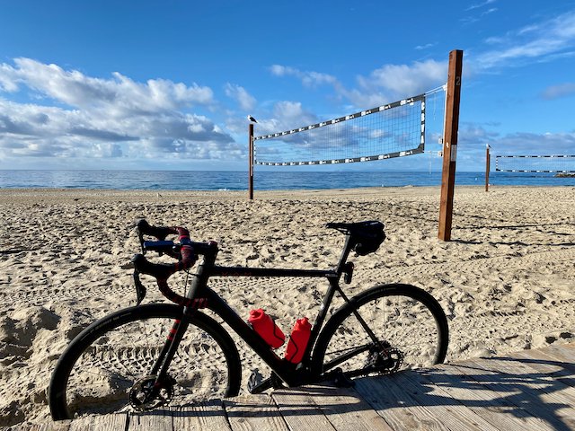 Factor O2 VAM bicycle in the sand near a volleyball court in Laguna Beach, California