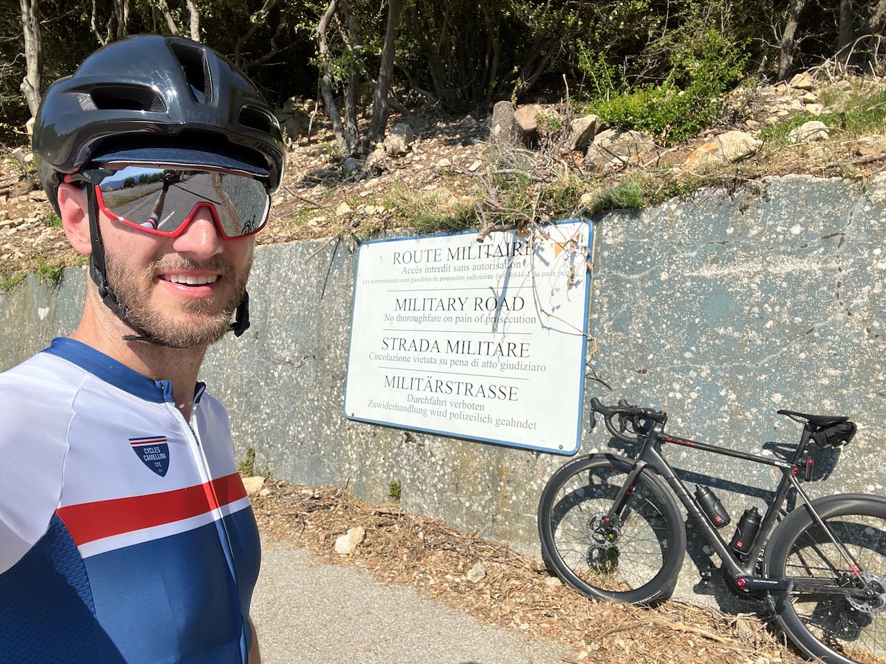 Cyclist standing in front of sign with bike near Mont Agel, France, just past the Monte Carlo Golf Club