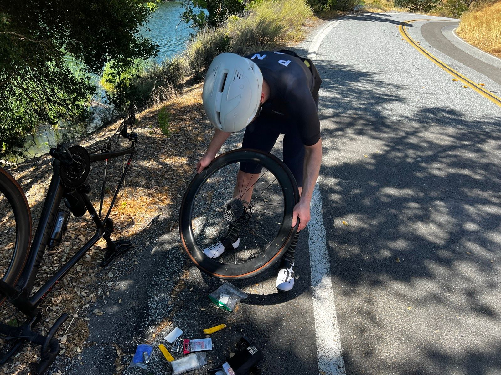 Cyclist changing out an inner tube inside a tubeless bike tire on the side of the road.