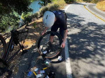 There I am, entire saddle bag dumped out on the side of the road. I also hate resting my bike upside down like that. Cyclist changing out an inner tube inside a tubeless bike tire on the side of the road.