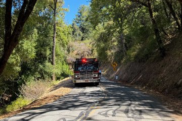 Fire truck from San Mateo County parked on West Alpine Road assisting two cyclists after a crash.