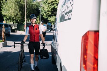 Cyclist with Factor O2 VAM bicycle with ScIcon Race Day Rain Bag in hand