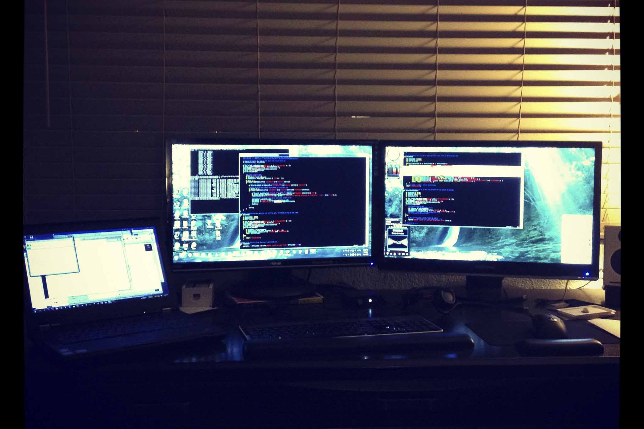 Dimly lit monitors on a computer desk