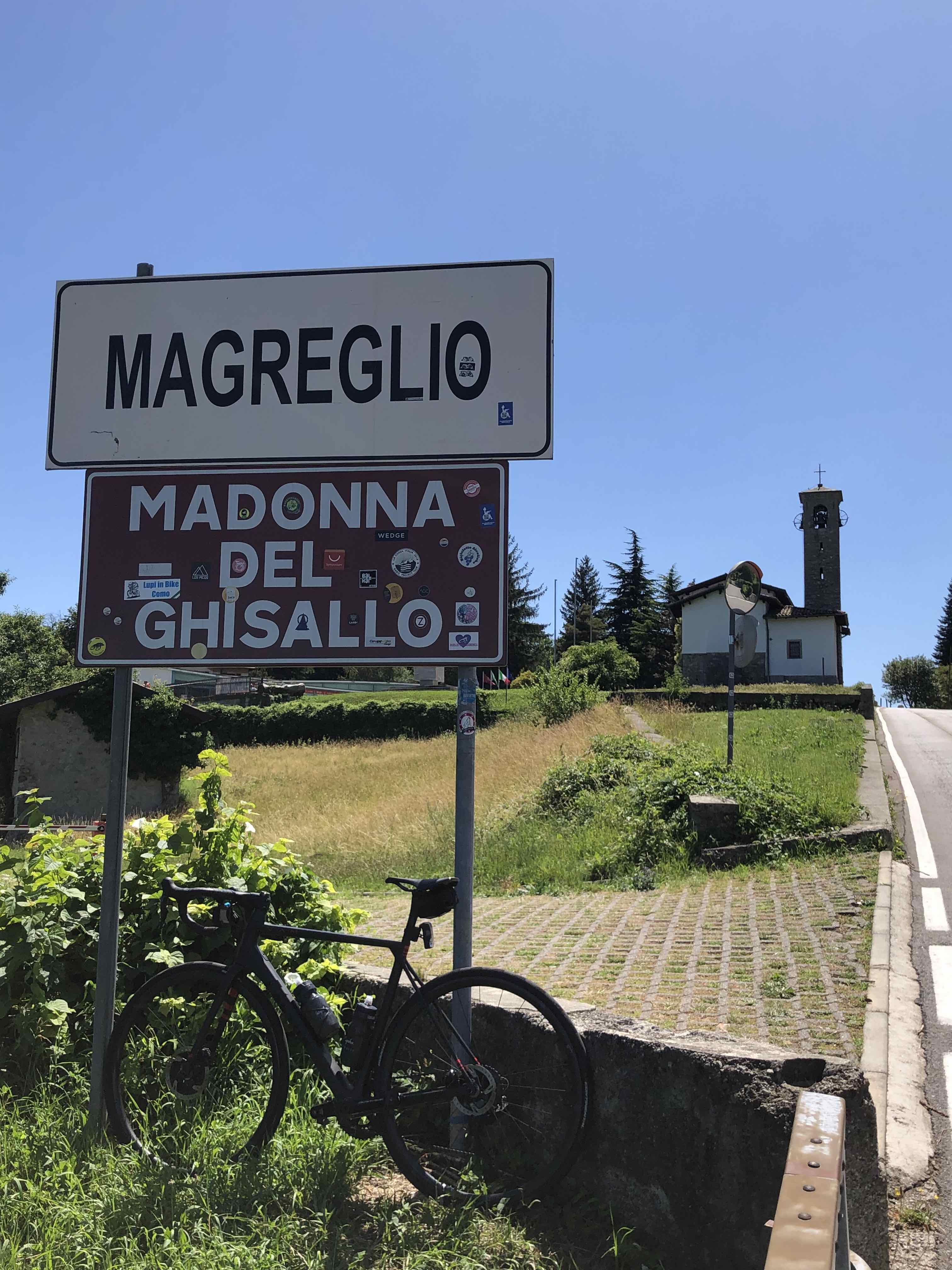 Road sign with bike parked in front marking the location for the Madonna del Ghisallo church near Bellagio, Italy