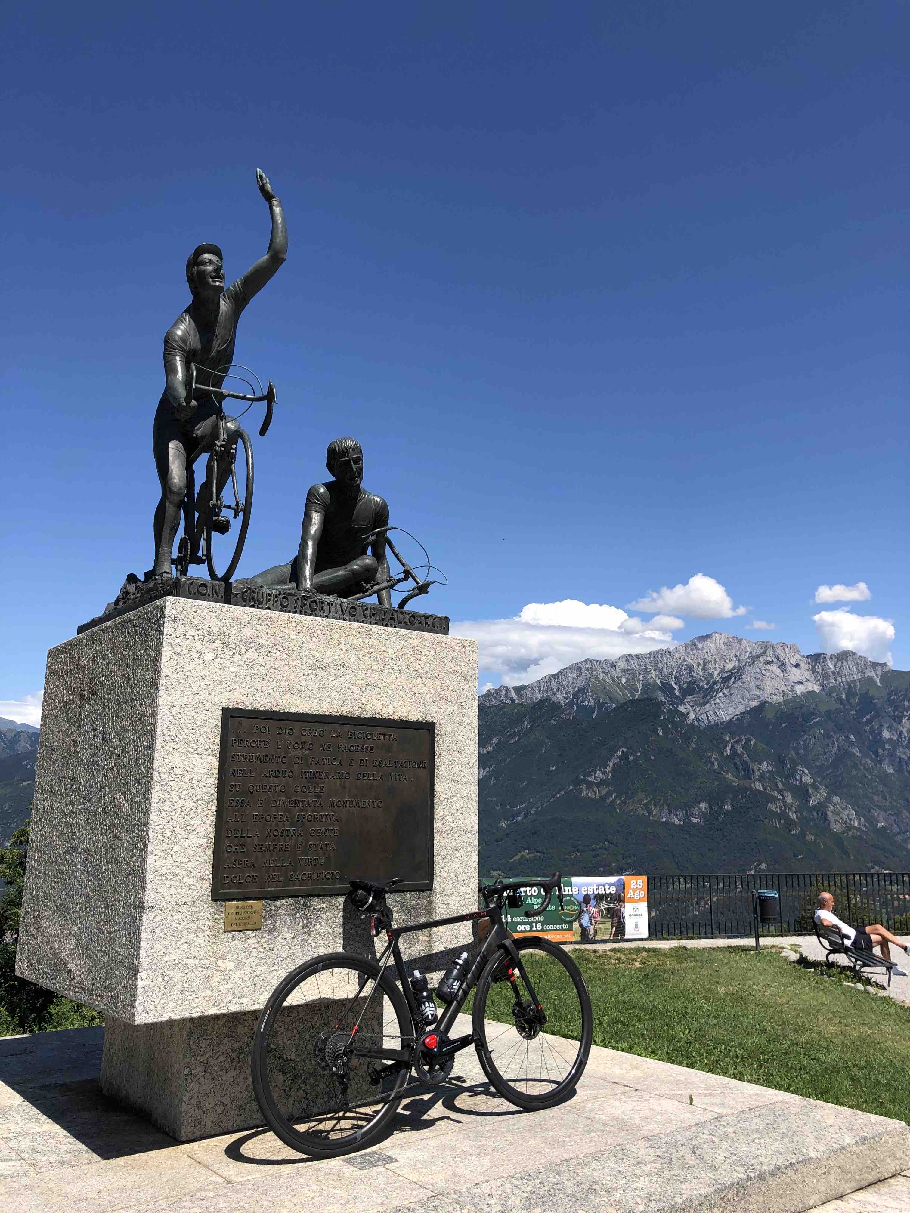 Famous statue of two bike riders with bicycle parked out front overlooking Lake Como