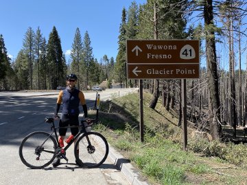 Here we go! Cyclist by the Glacier Point turnoff road sign in Yosemite National Park.