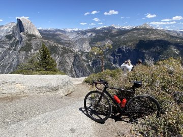 There are typically a lot of people up there, as it's a popular destination to drive to. Factor O2 VAM bike resting in bushes at Glacier Point in Yosemite National Park with view out over Half Dome.