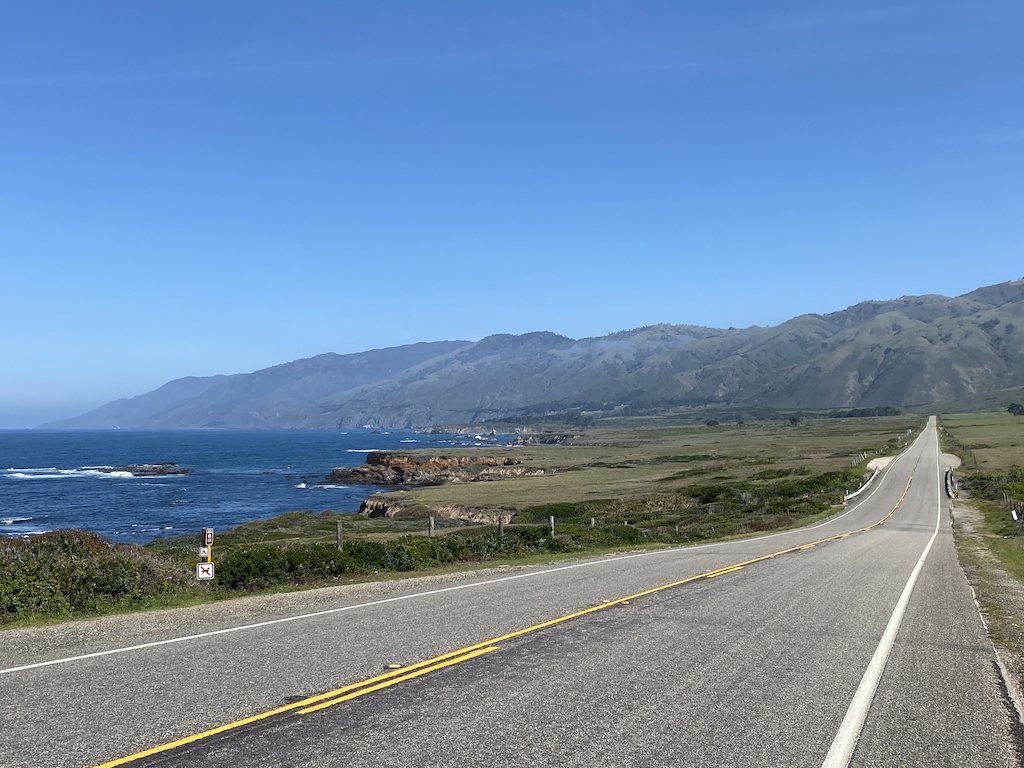 View out over the ocean north of San Simeon, California, showing a straight road with beautiful undulating bumps leading up to Ragged Point