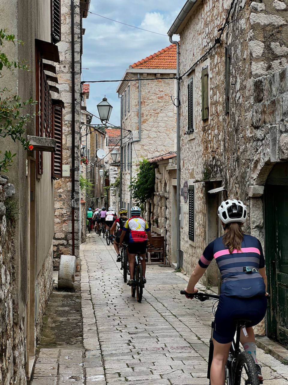 Cyclists riding through a tiny cobbled street near Stari Grad, Croatia