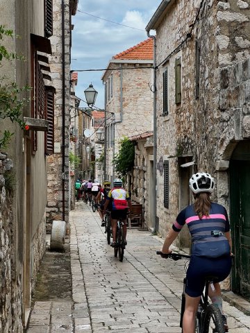 We saw a bunch of these tiny streets all throughout Croatia Cyclists riding through a tiny cobbled street near Stari Grad, Croatia