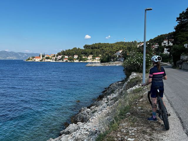 Cyclist along frontage road looking out towards Korcula town in Croatia