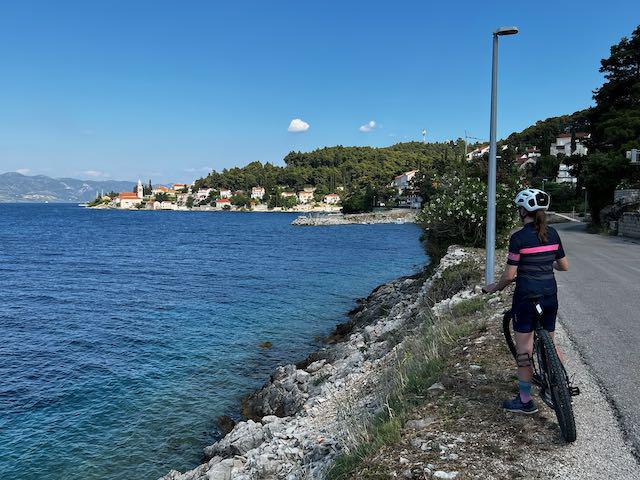 Cyclist along frontage road looking out towards Korcula town in Croatia