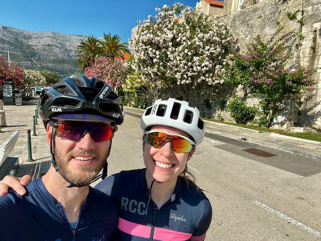 Cyclists in Korcula town near the city wall and the beautiful pink and purple flowers