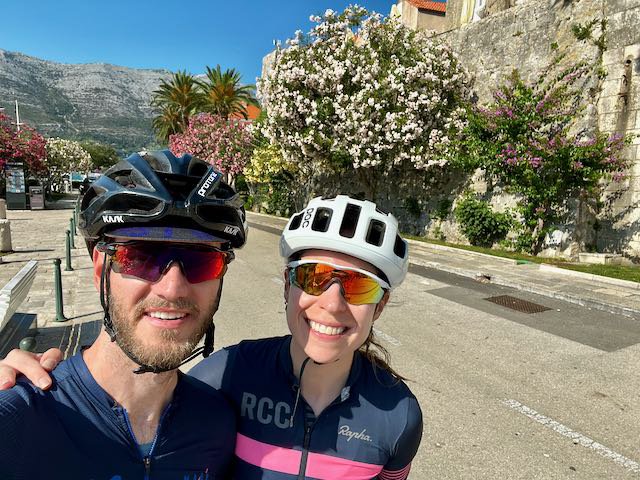 Cyclists in Korcula town near the city wall and the beautiful pink and purple flowers