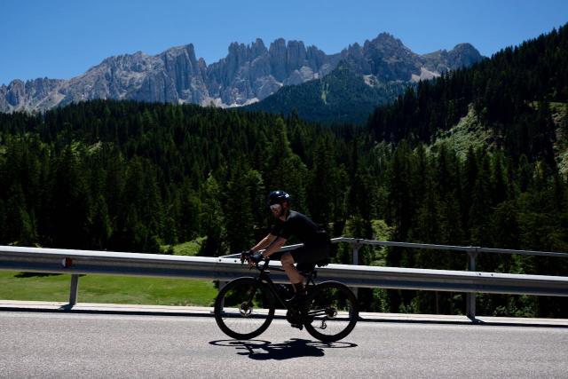Cyclist riding into the Dolomites near the Passo Costalunga