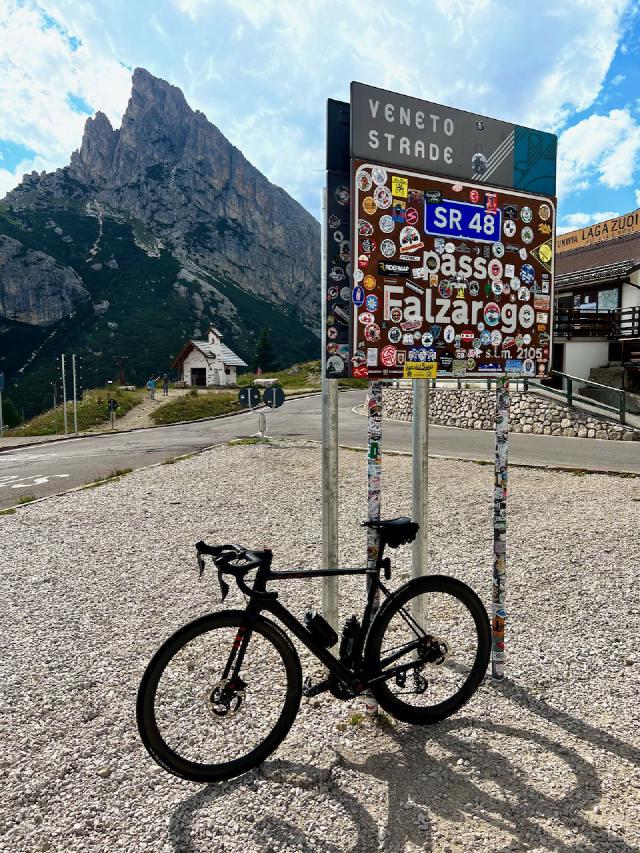 Factor O2 VAM bicycle leaning against the Passo Falzarego sign