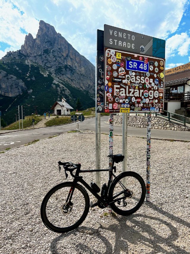 Factor O2 VAM bicycle leaning against the Passo Falzarego sign