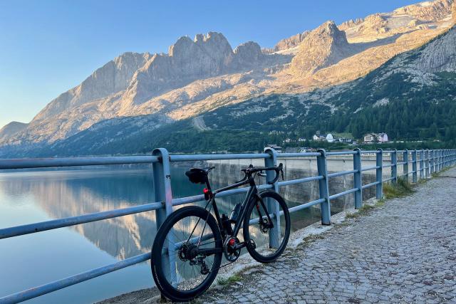 Factor O2 VAM bicycle leaning against a fence at the Passo Fedaia with Lago della Fedaia behind