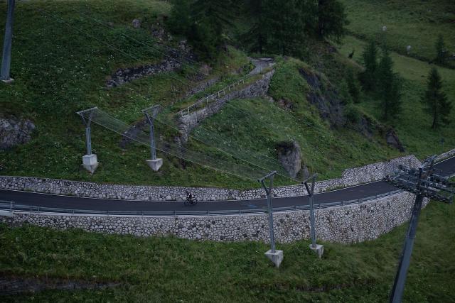 Distance shot of a cyclist climbing up the Passo Fedaia crossing underneath the skilift nets