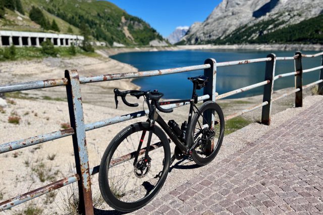Factor O2 VAM bicycle leaning against a fence at the Passo Marmolada / Fedaia overlooking the lake.