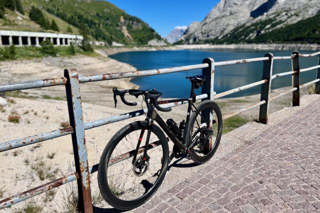 Factor O2 VAM bicycle leaning against a fence at the Passo Marmolada / Fedaia overlooking the lake.