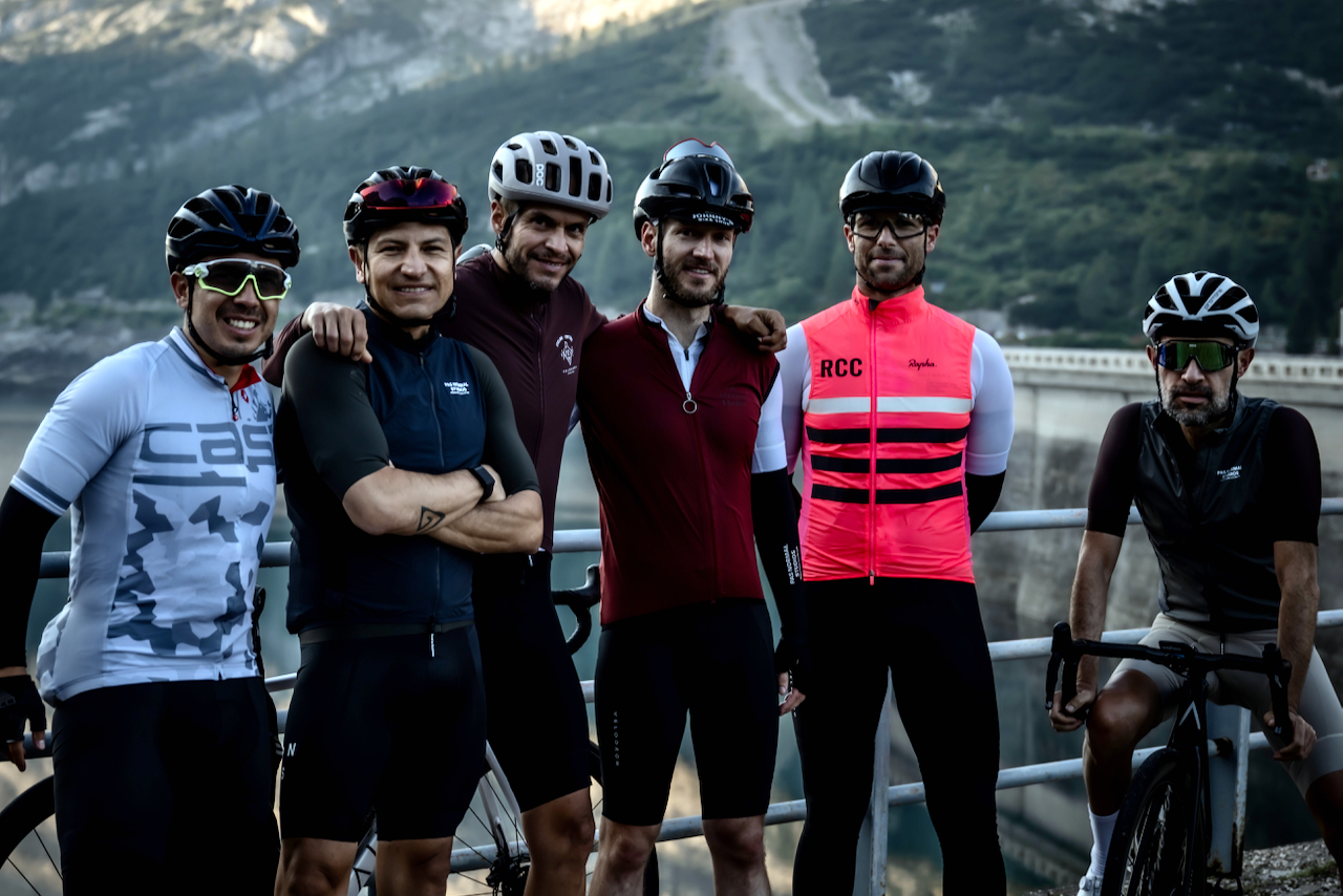 Group of cyclists posing near the lake on the Passo Fedaia in the morning light