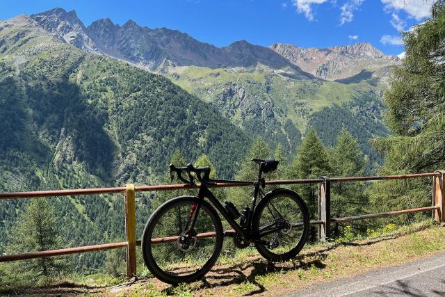 Factor O2 VAM bicycle leaning against a fence overlooking a view of mountains on the Passo Gavia climb