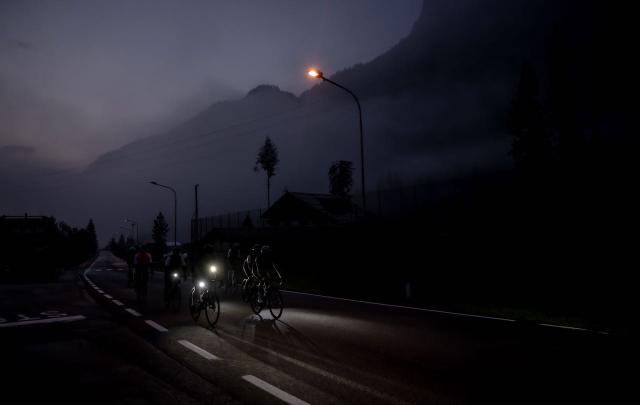Cyclists climbing the Passo Fedaia with headlights before sunrise