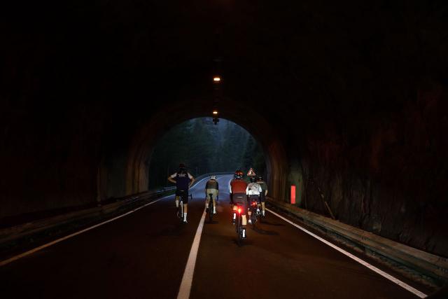 Cyclists riding through a tunnel on the way up to the Passo Fedaia in the morning light