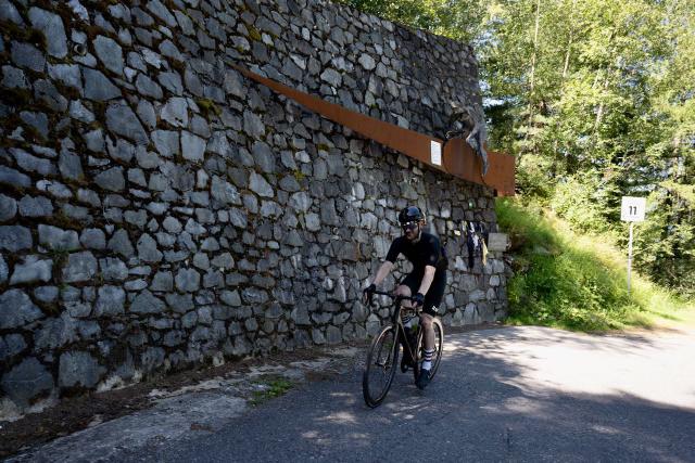 Cyclist pedaling near the Marco Pantani monument on turn 11 of the Mortirolo climb