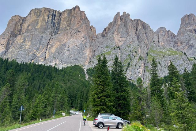 Cyclist on road to the Passo Sella with parked cars nearby