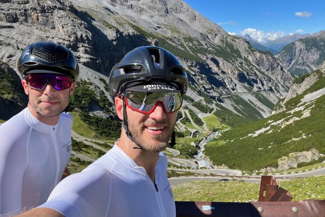 Two cyclists looking back down on the Stelvio climb from the Bormio side