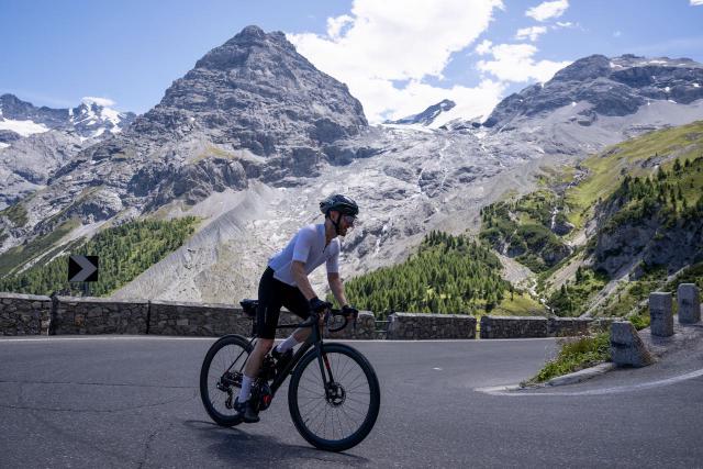 Cyclist climbing the Passo dello Stelvio from Trafoi in Italy with mountains and glaciers in the background
