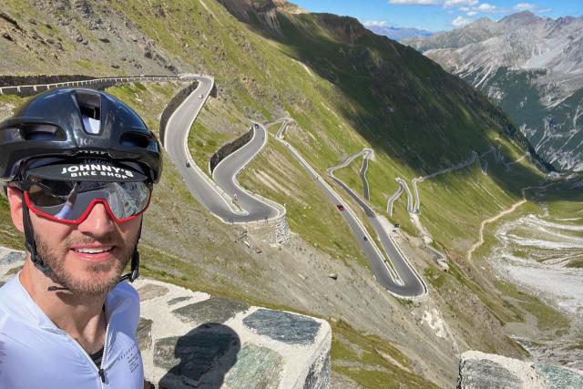 Iconic cyclist selfie from the top of the Passo dello Stelvio looking down on the switchback road