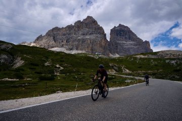 Disc brakes ftw on this one! Cyclist descending down the Tre Cime di Lavaredo climb with Tre Cime di Lavaredo in the background