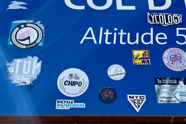 Stickers on blue sign of the Col d'Éze in Nice, France