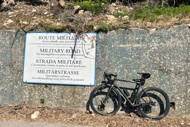 Factor O2 VAM bicycle leaning against wall next to Mont Agel base sign showing no trespassing