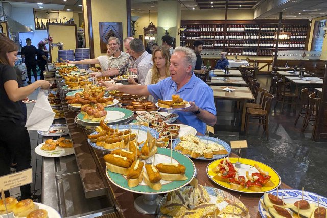 Basque inspired small plate food items at a restaurant being selected by people over a counter.