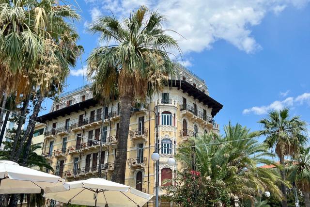 Building with palm tress against a blue sky in Sanremo, Italy