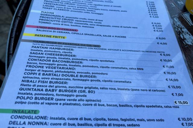Menu of the La Cueva cafe in Sanremo, Italy, showing burgers named after professional cyclists