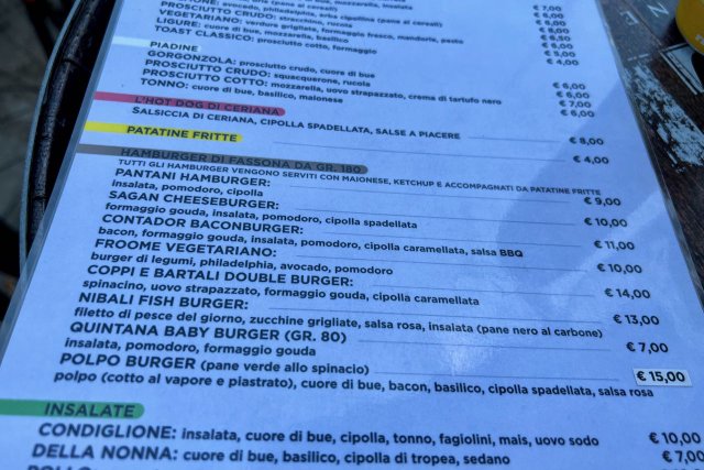 Menu of the La Cueva cafe in Sanremo, Italy, showing burgers named after professional cyclists