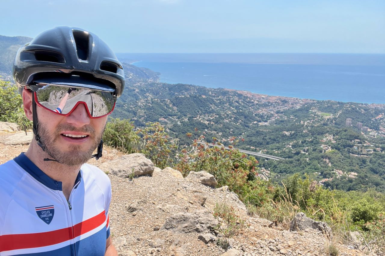 Cyclist riding the Col de la Madone with the Mediterranean Sea in the background