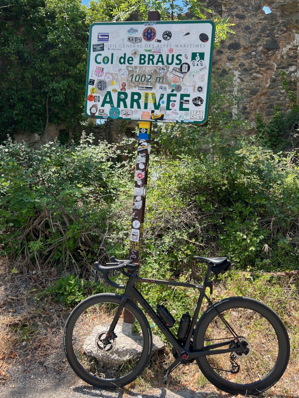Factor O2 VAM bicycle leaning against the Col de Braus sign at the top of the climb