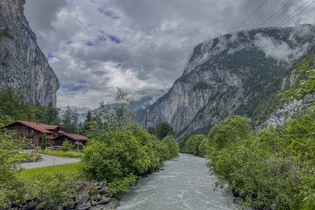 View over the Lauterbrunnen valley with a river, mountains, and rainy clouds